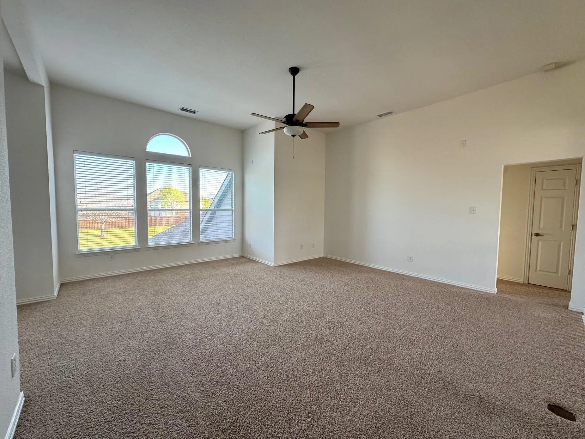 Expansive room featuring vaulted ceilings, a ceiling fan, and multiple windows with an arched transom