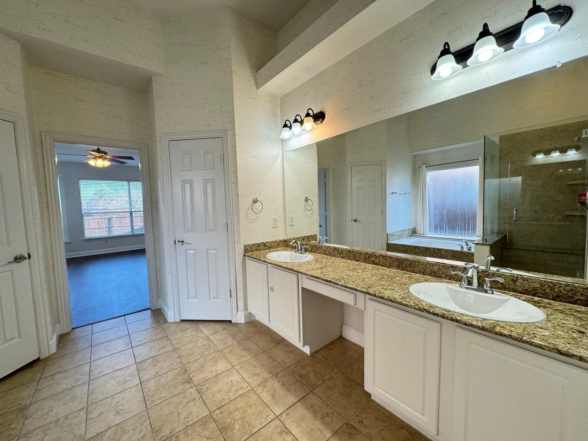 Dual vanity with undermount sinks, stone-finish countertops, and an expansive wall mirror