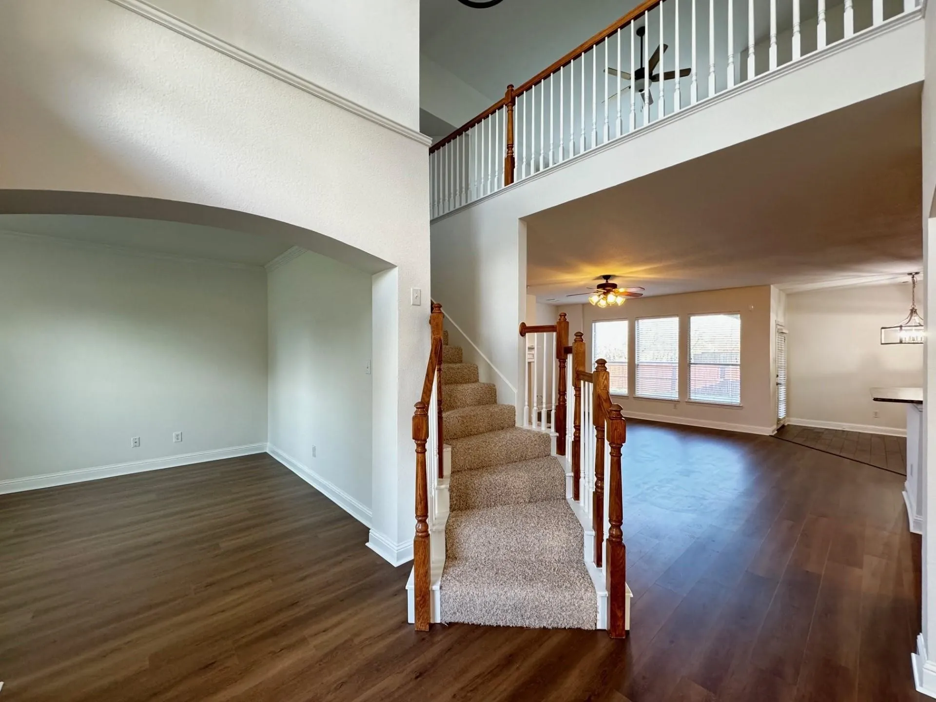 Two-story foyer with carpeted staircase, wood-finish flooring, and an arched entry