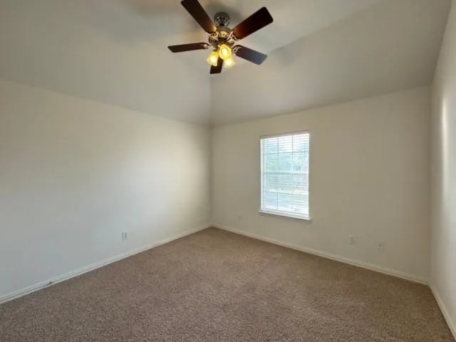 Vaulted ceiling with a ceiling fan, neutral wall paint, and carpet flooring