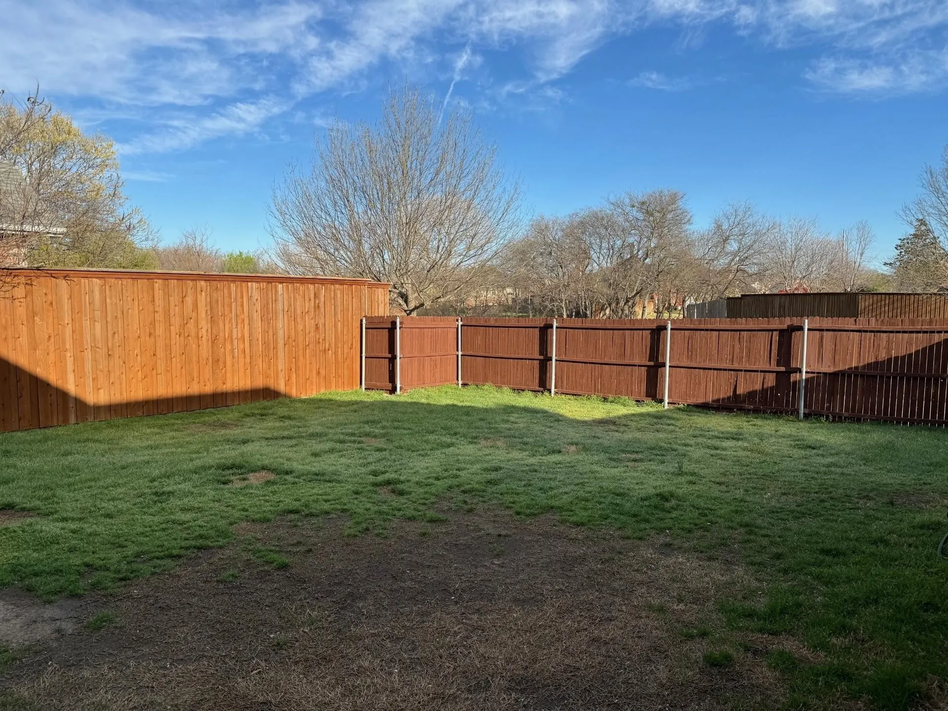 Fenced backyard with a combination of light wood-tone and dark wood-tone privacy fencing