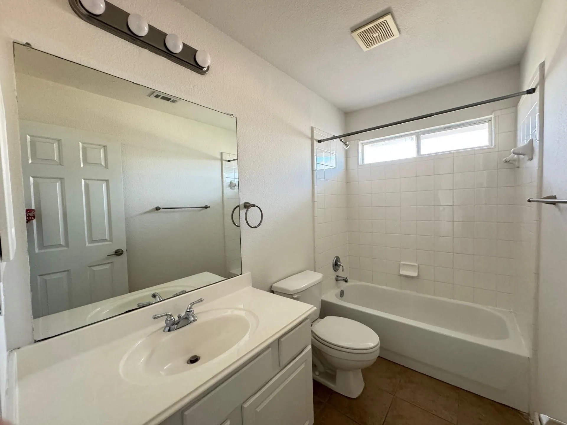 Bathroom with a single vanity, large mirror, and full-size tub with overhead shower