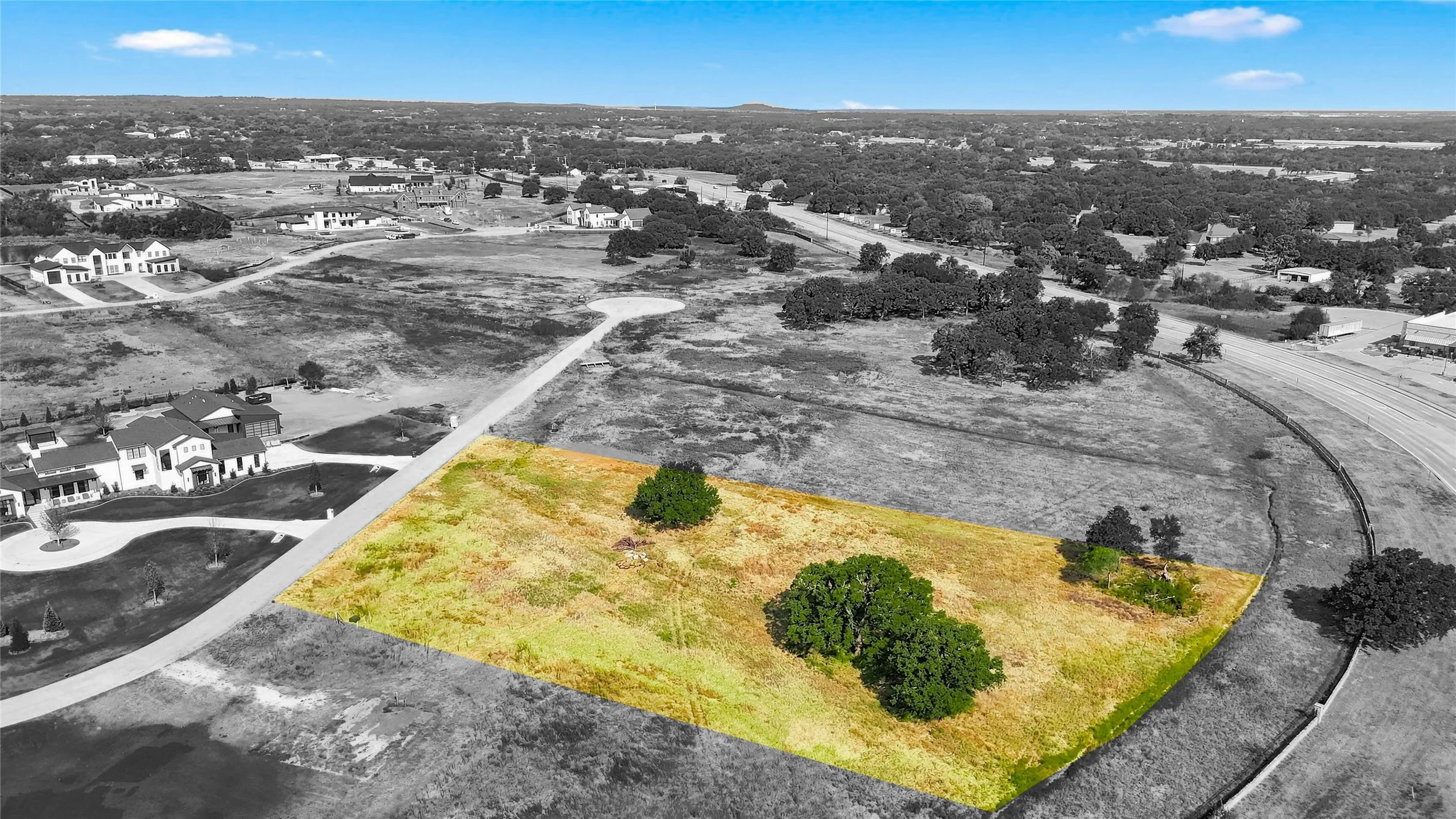 Expansive lot with natural terrain, mature trees, and paved road access