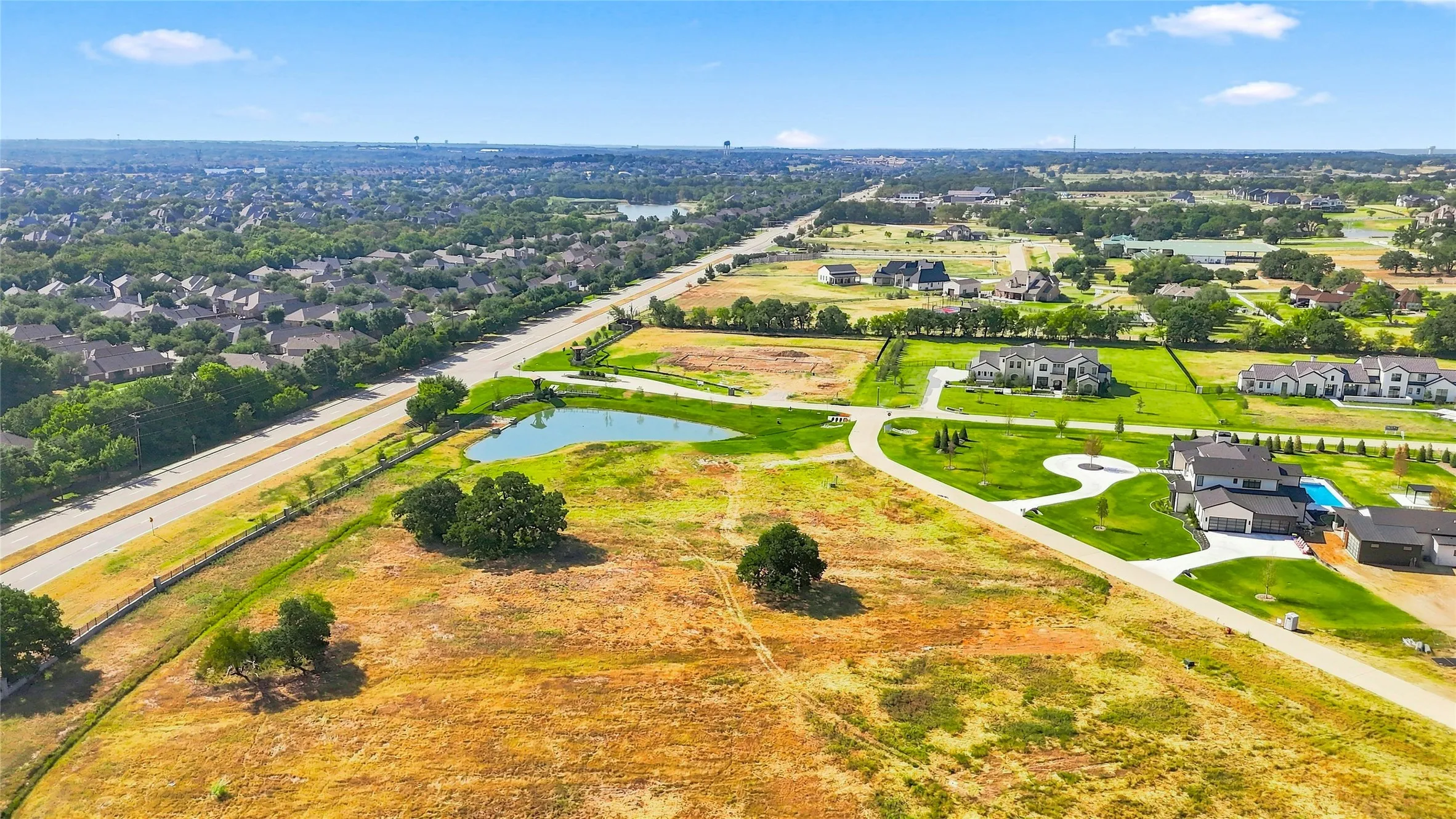 Expansive property featuring a private pond, mature trees, and a developed residential area
