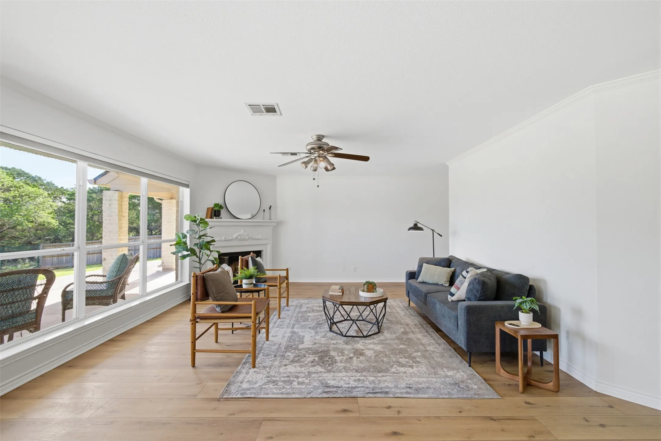 Bright interior space featuring wood-finish flooring, a white mantel, and a ceiling fan