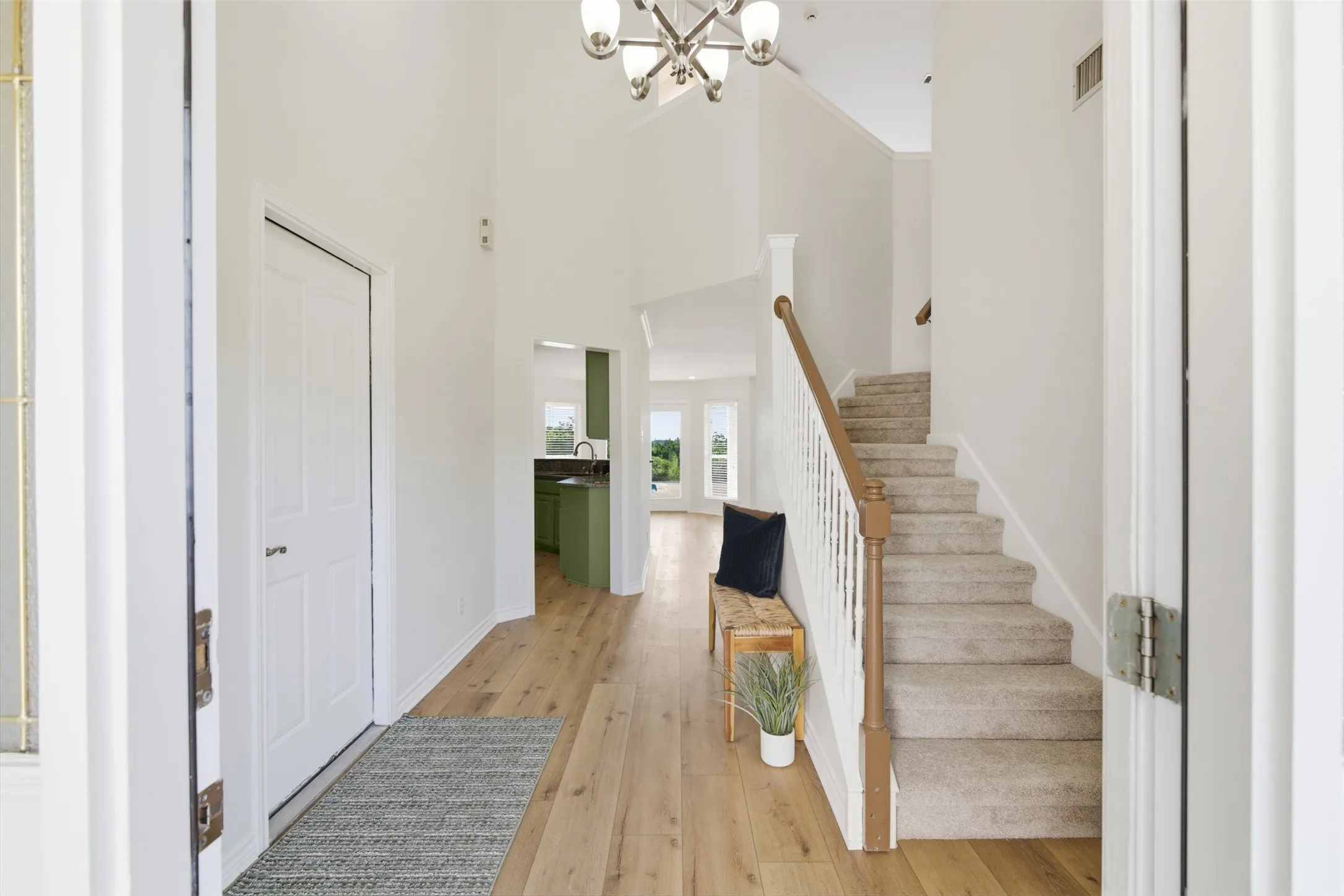 Foyer with vaulted ceiling, wood-finish flooring, and a carpeted staircase with a wood handrail