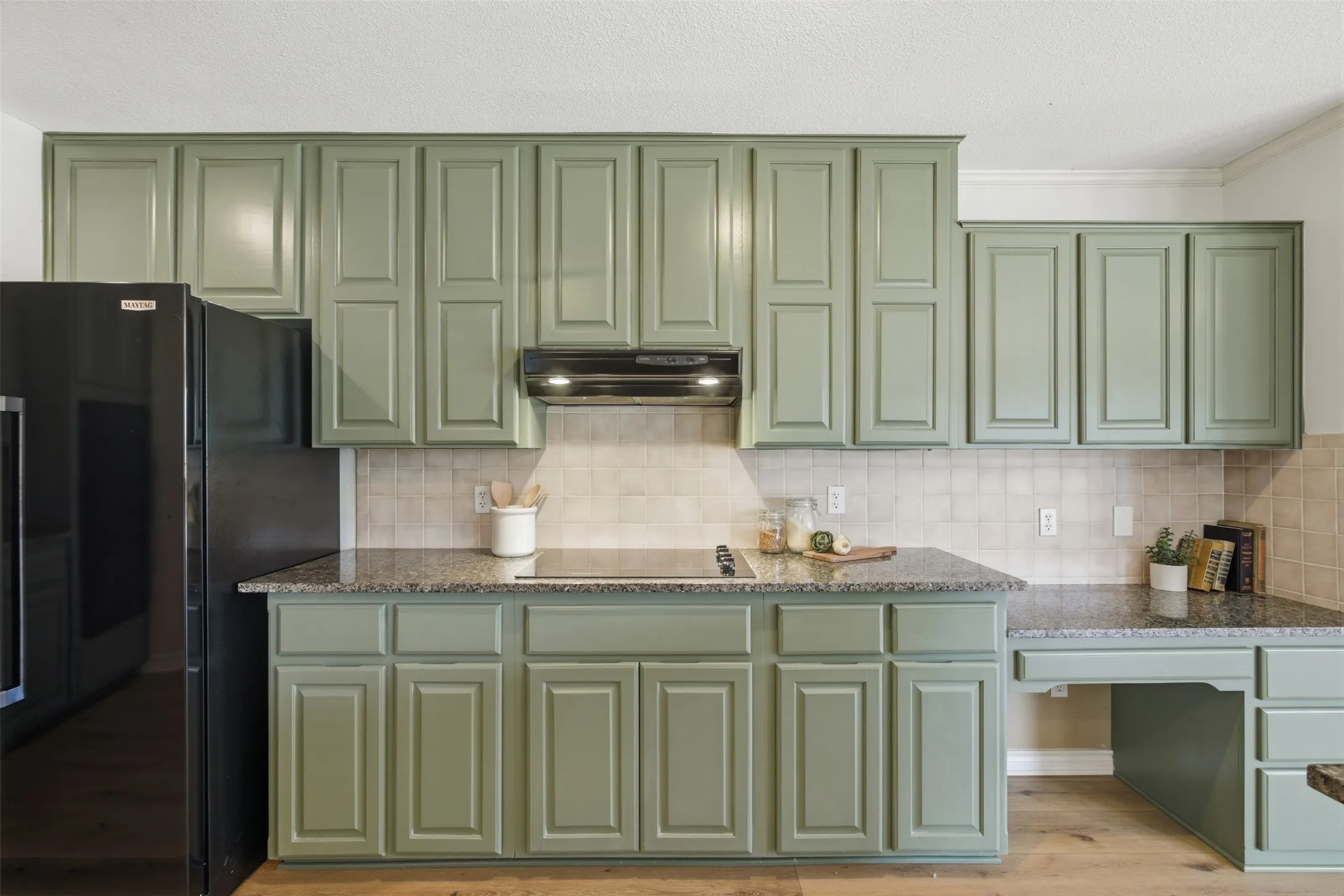 Kitchen featuring panel-front cabinetry, stone-finish countertops, ceramic tile backsplash, and wood-finish flooring