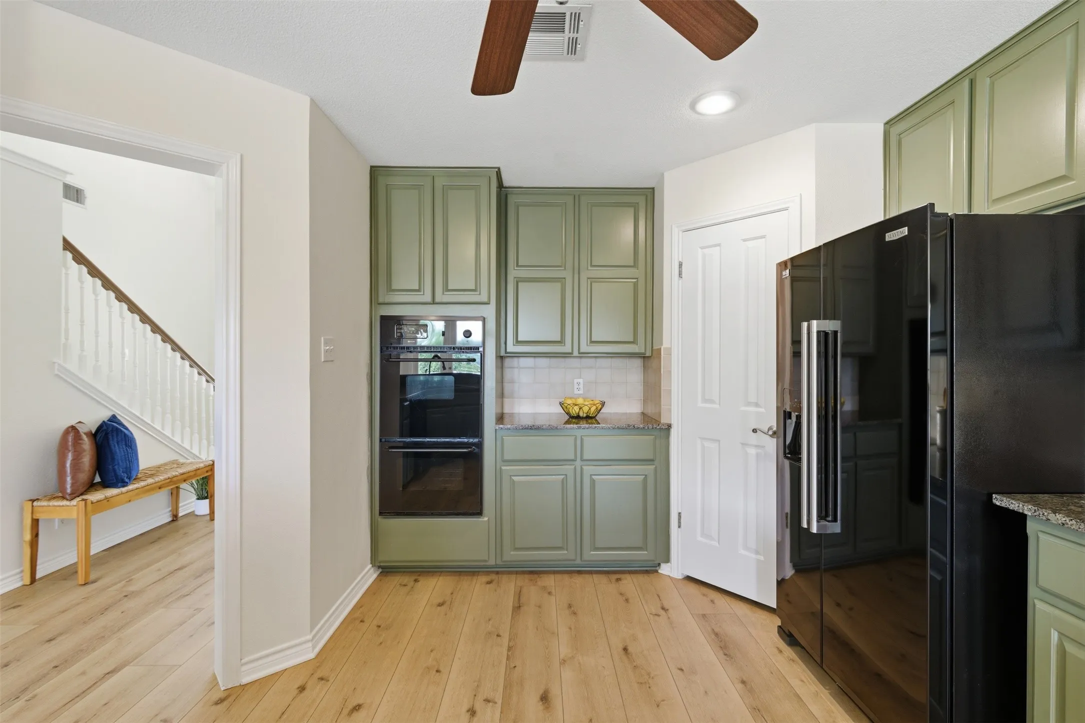 Wood-finish flooring, recessed lighting, ceiling fan, sage green cabinetry, built-in double oven