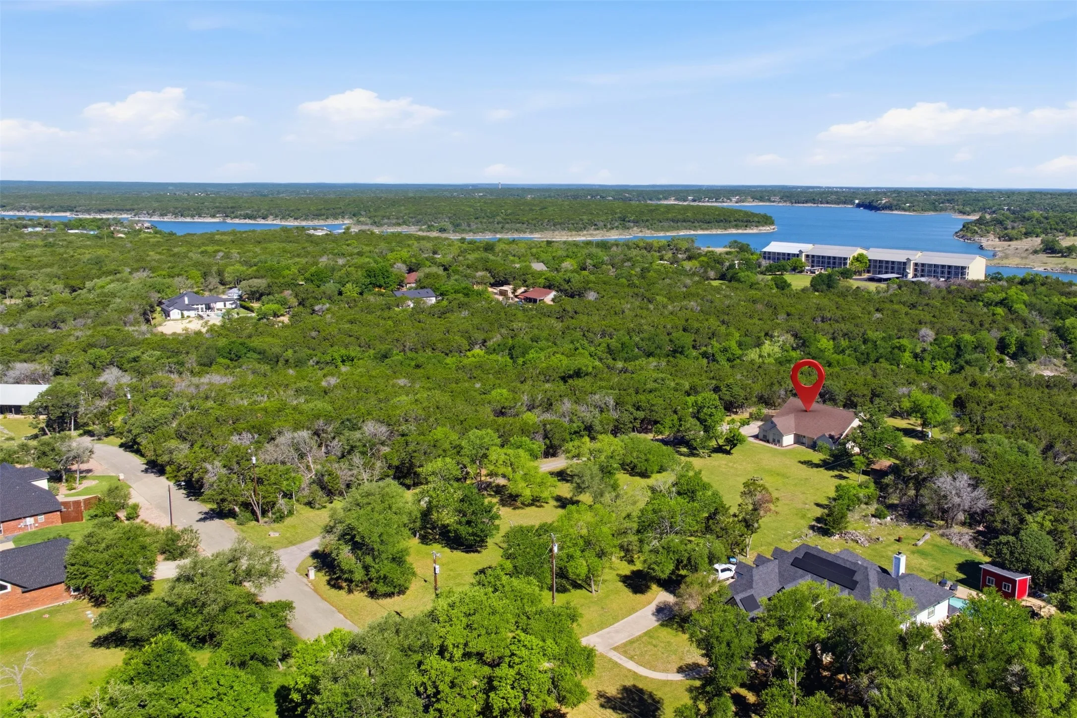 Property set amidst extensive tree coverage with a visible body of water in the background