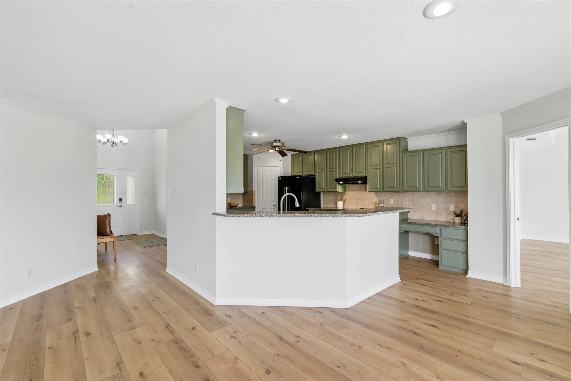 Wood-finish flooring, recessed lighting, kitchen with green cabinetry, granite countertops, and a built-in desk area