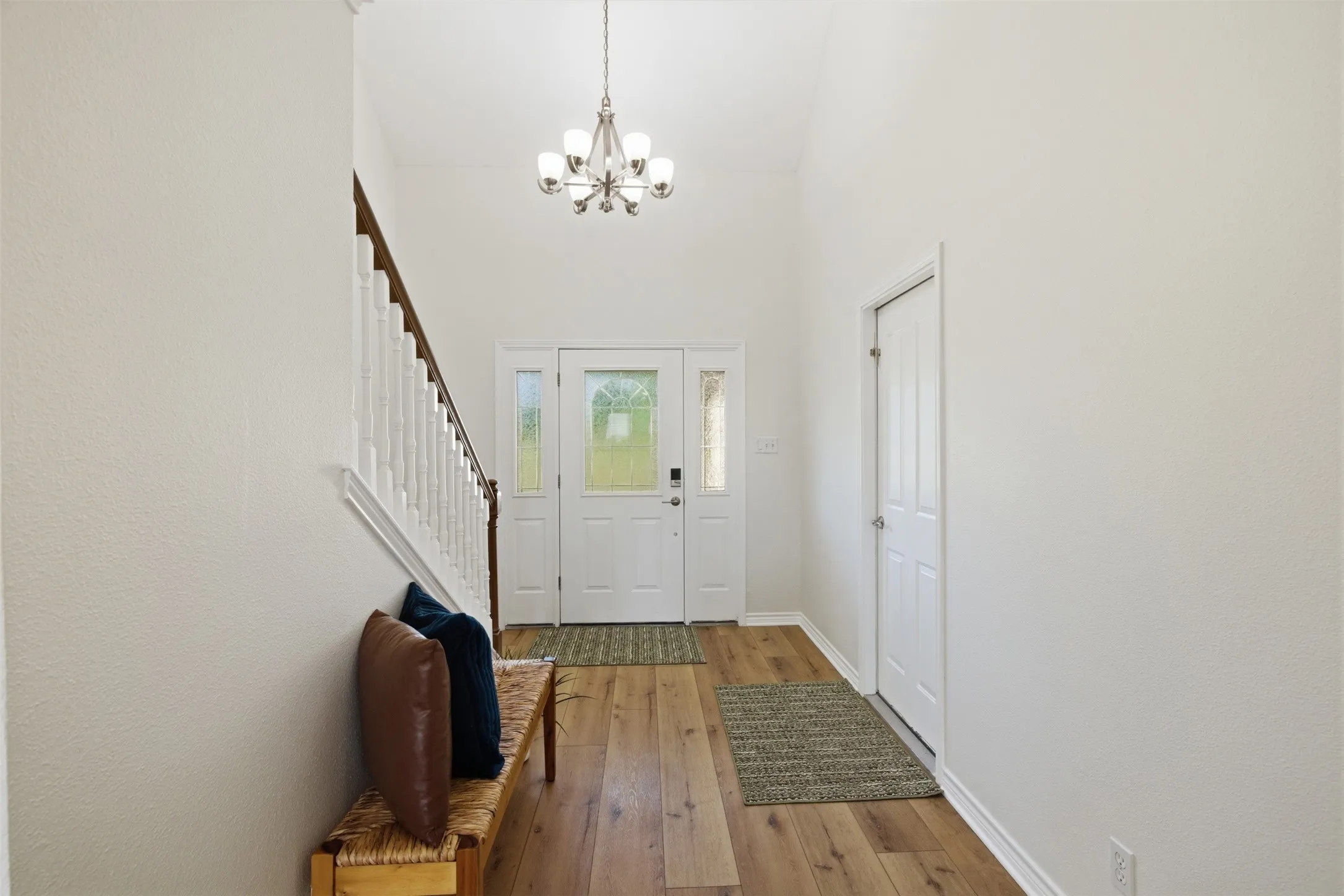 Foyer with a vaulted ceiling, wood-finish flooring, and a six-light chandelier