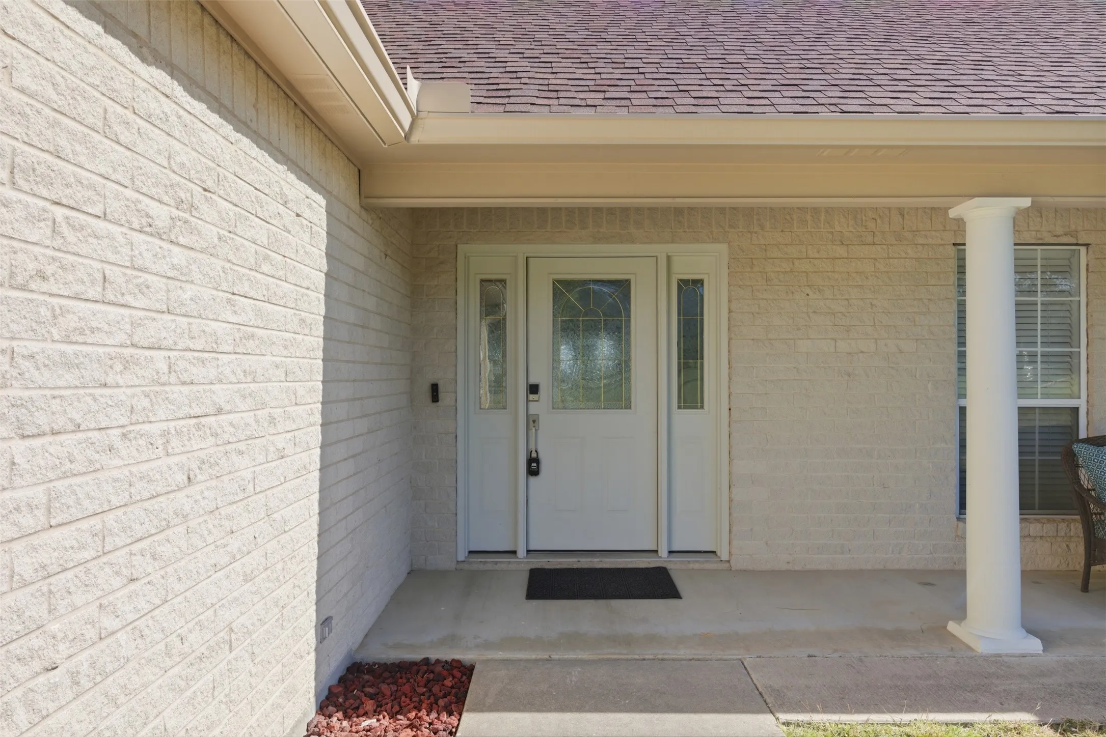 Cream brick exterior featuring a covered entry