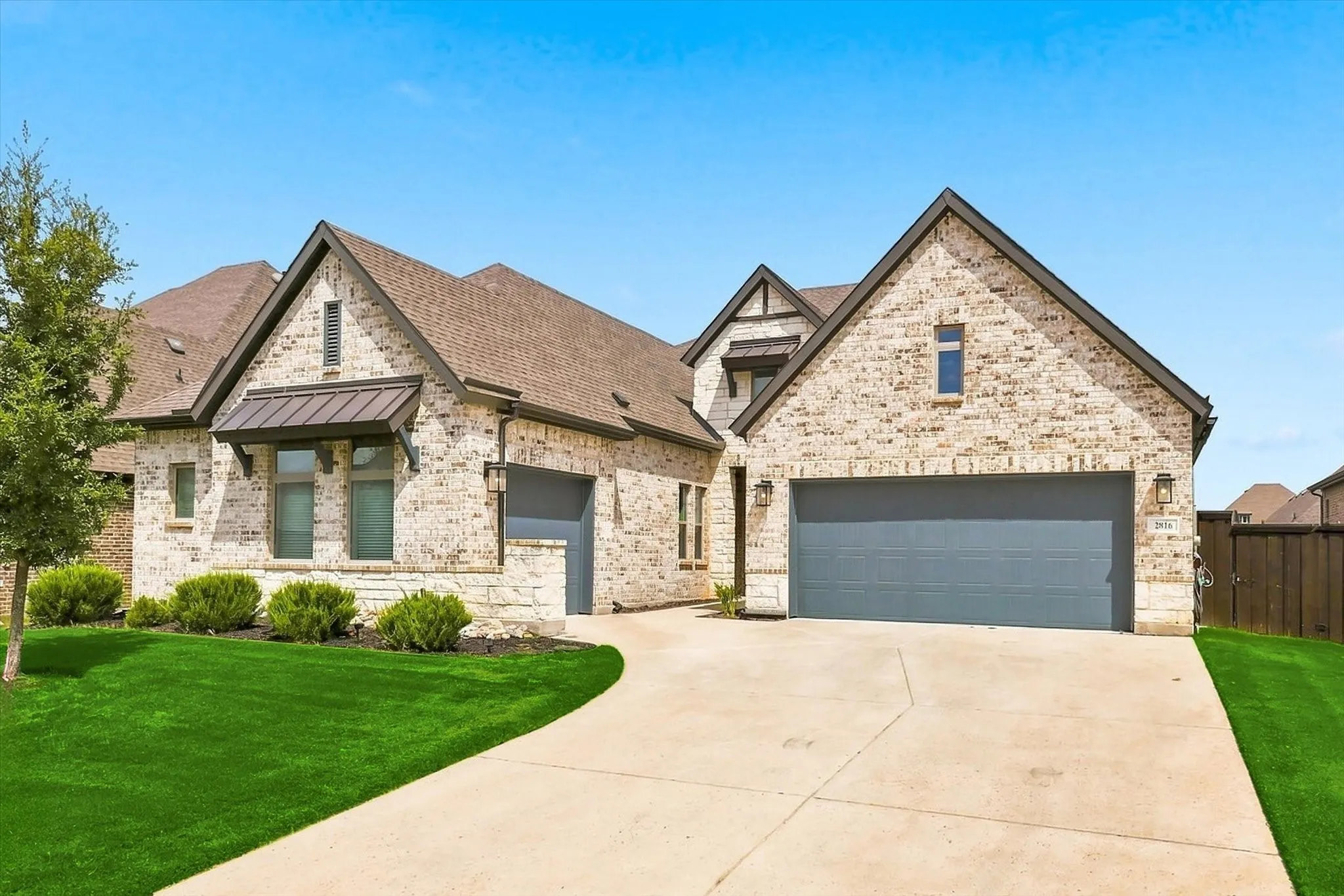 Light-colored brick exterior with stone accents, featuring a multi-gabled roofline and dark trim