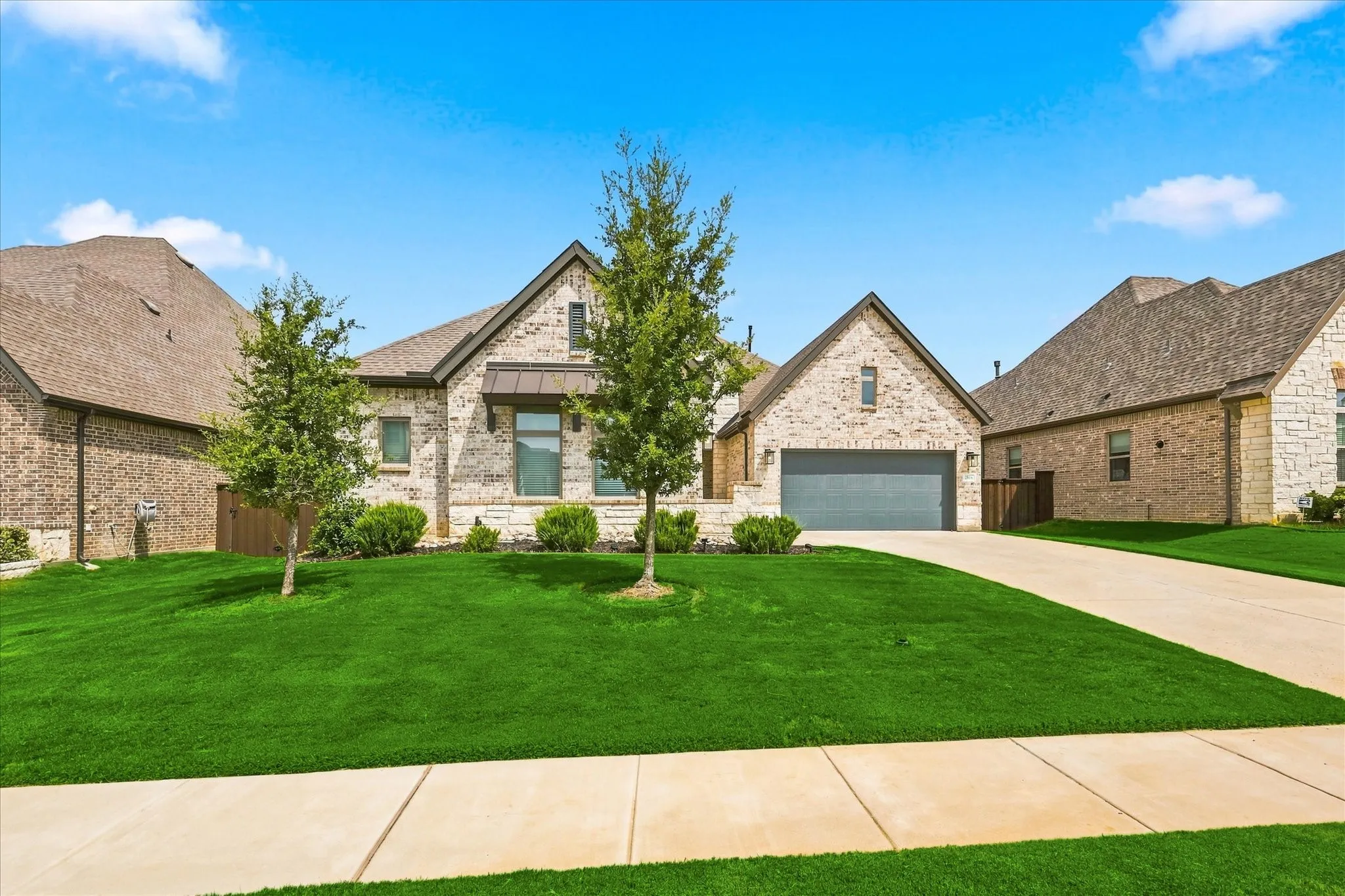 Brick and stone exterior with a gabled roofline, attached garage, and a concrete driveway