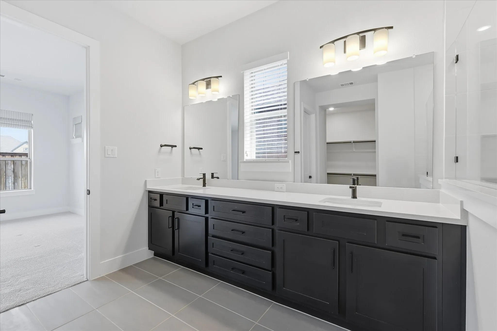 Dual vanity with dark cabinetry, white countertops, and matte black fixtures