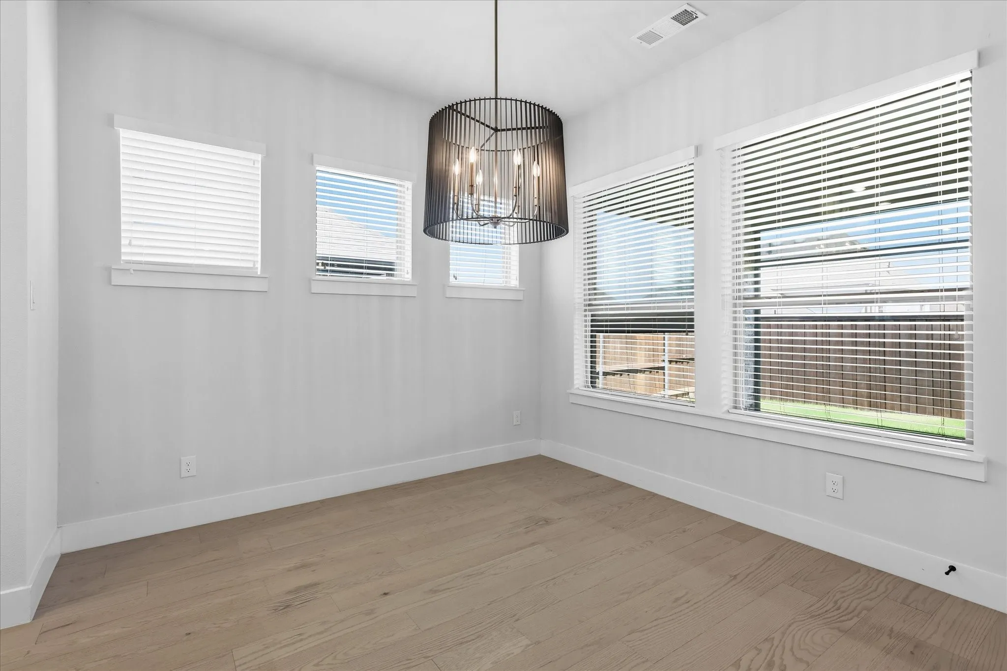 Wood-finish flooring, multiple windows with blinds, and a contemporary chandelier fixture