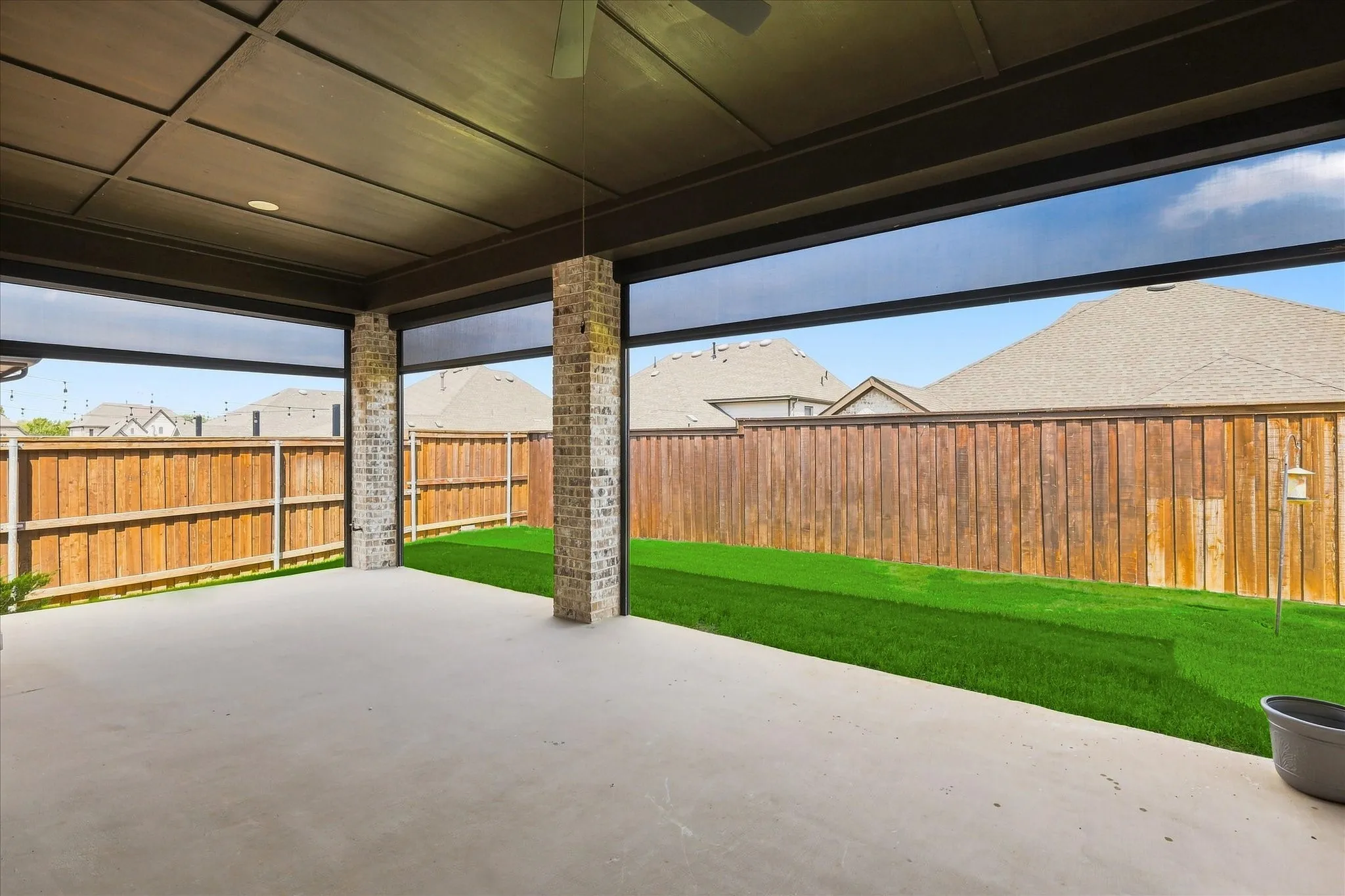 Covered patio with a coffered ceiling, brick support columns, and a ceiling fan