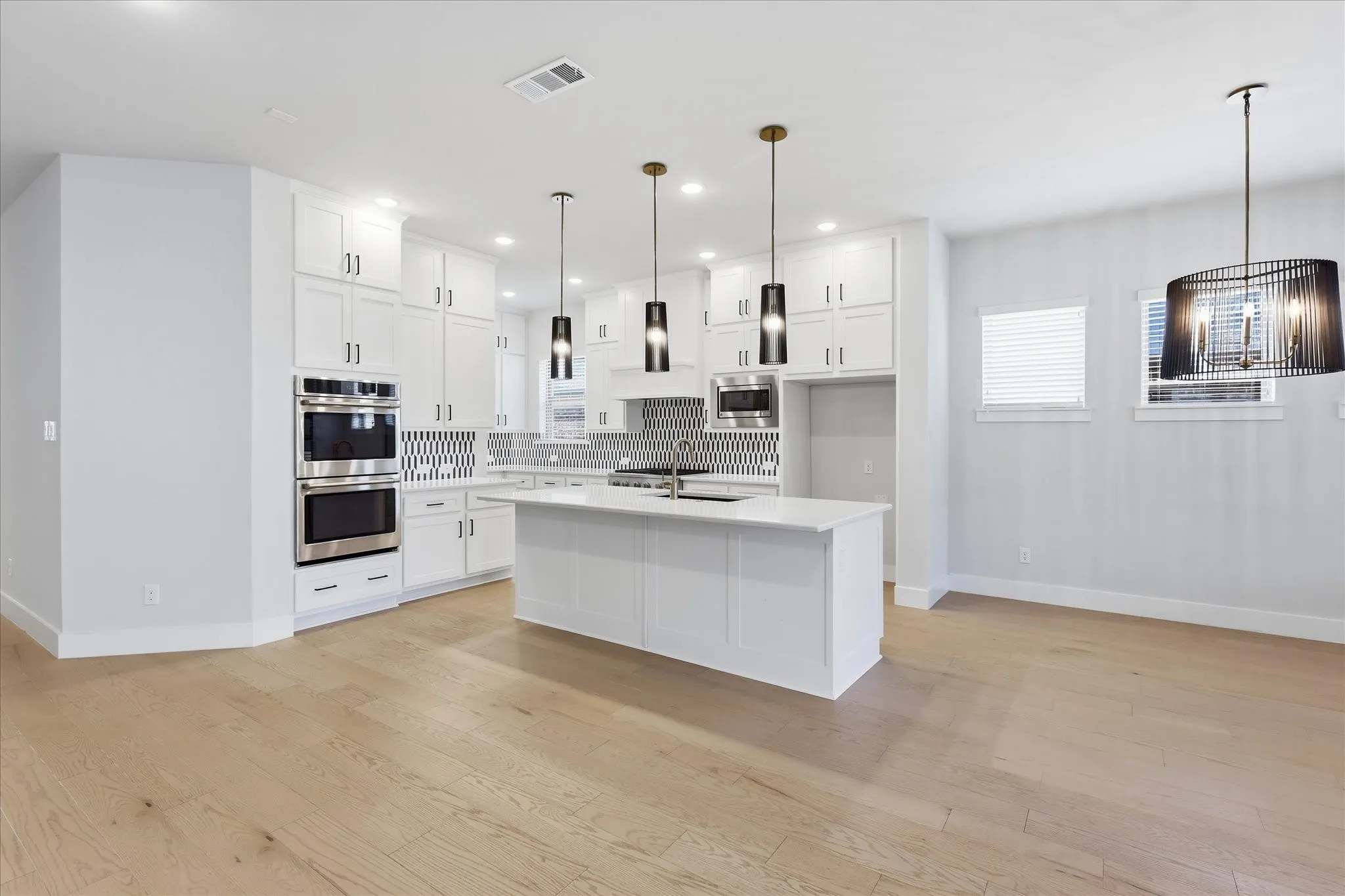 Contemporary kitchen featuring white cabinetry, a center island, stainless steel double ovens, and a patterned tile backsplash