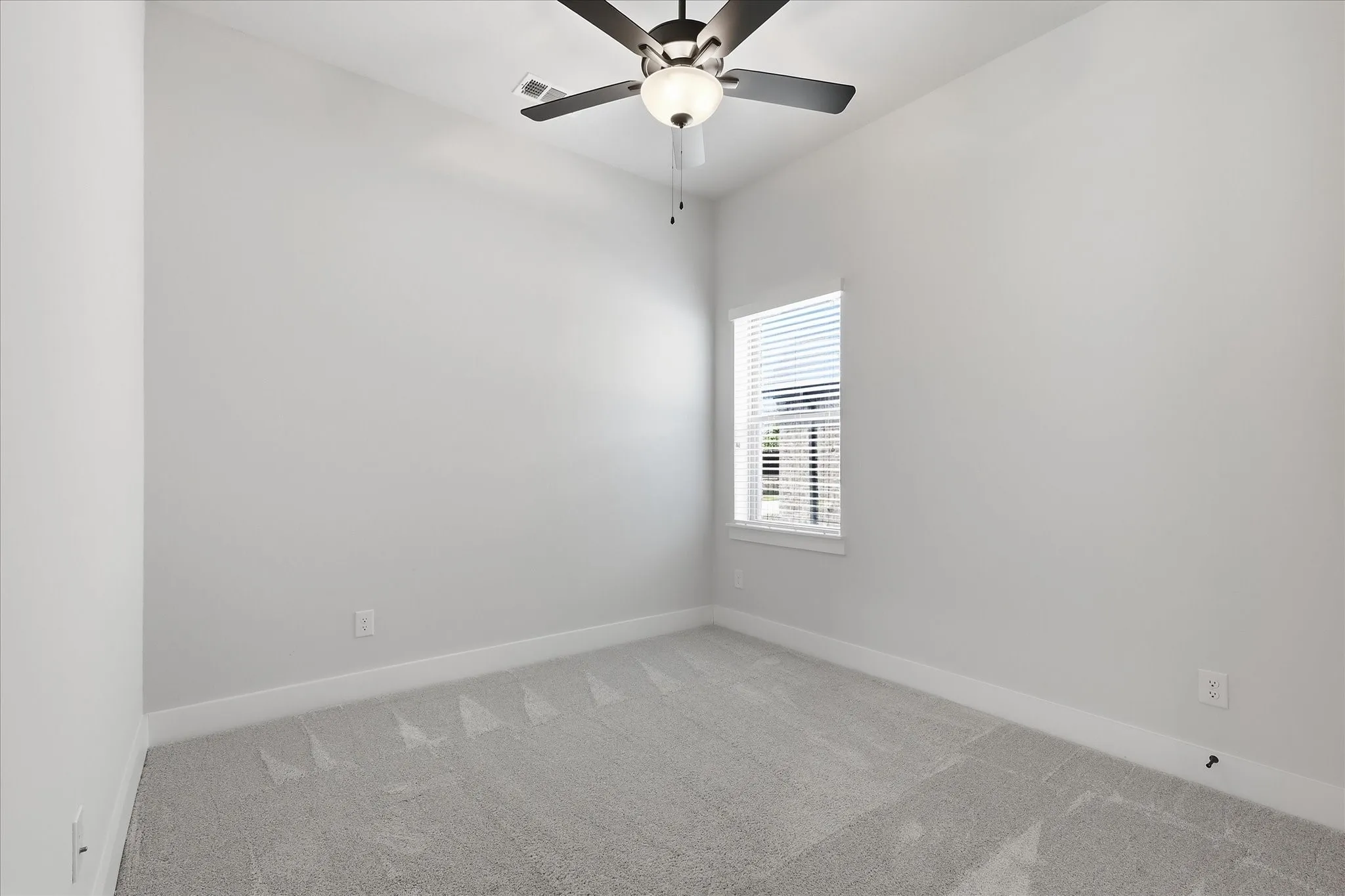 Neutral toned walls, recessed window with blinds, and a ceiling fan with integrated lighting