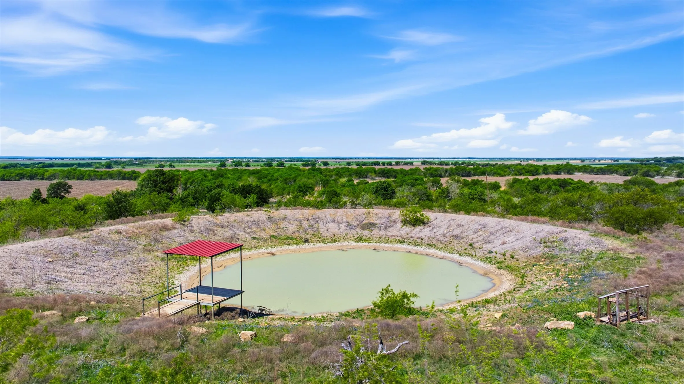 Circular pond with a fixed dock featuring a red roof