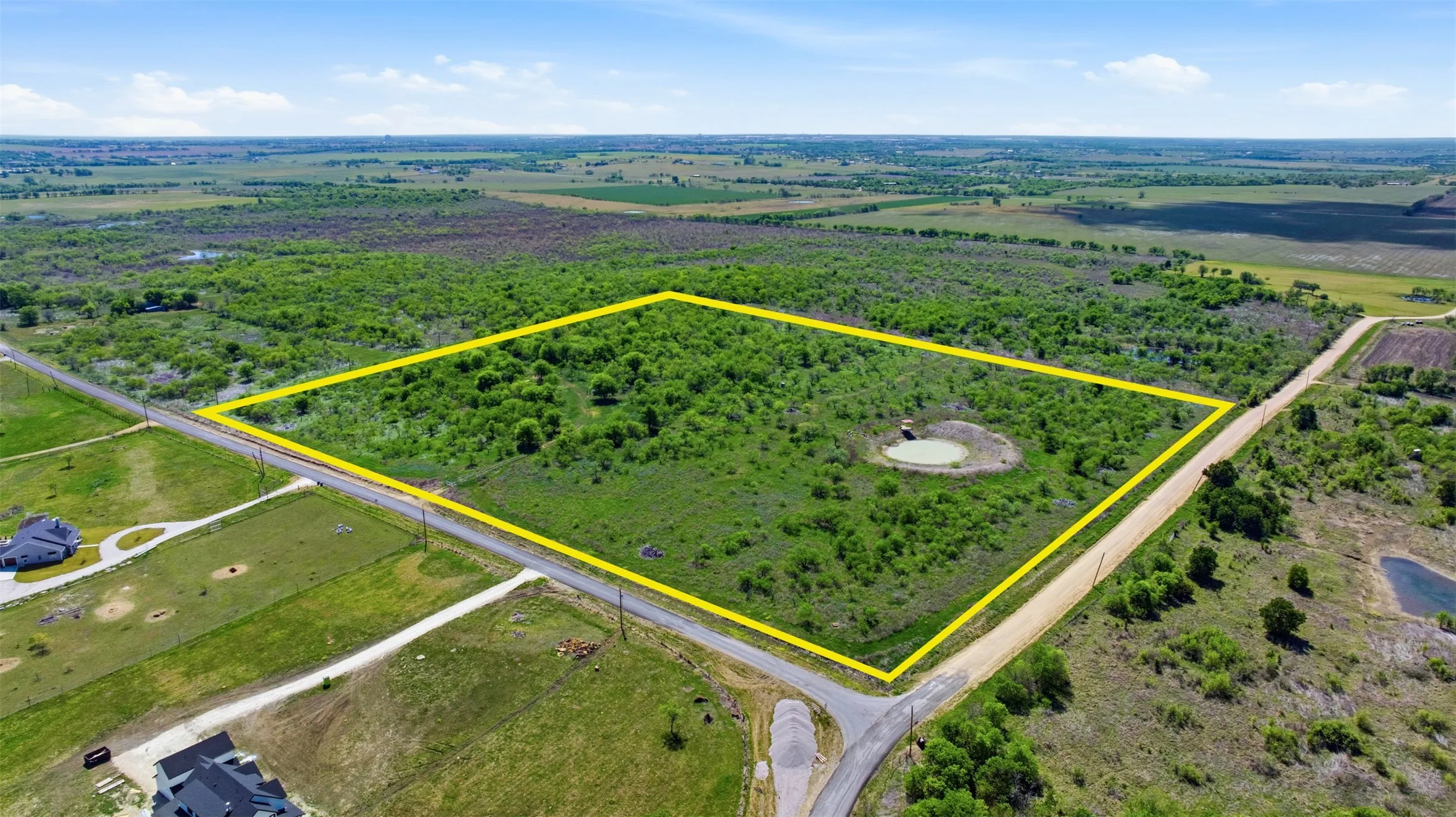 Expansive raw land parcel featuring natural vegetation and a small pond