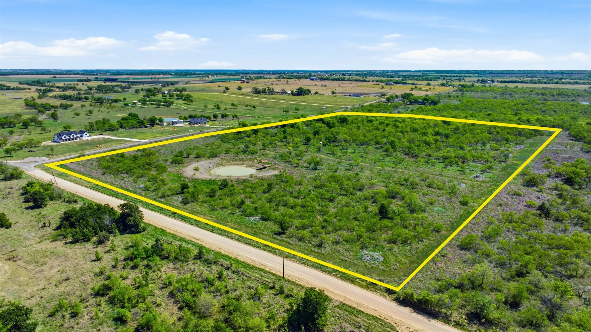 Expansive land parcel featuring a natural pond, dense natural vegetation, and a clear perimeter