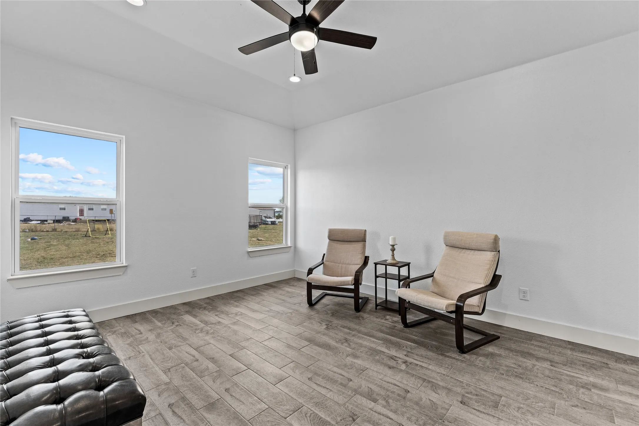 Recessed lighting, ceiling fan with light fixture, two windows, wood-finish flooring, and white walls