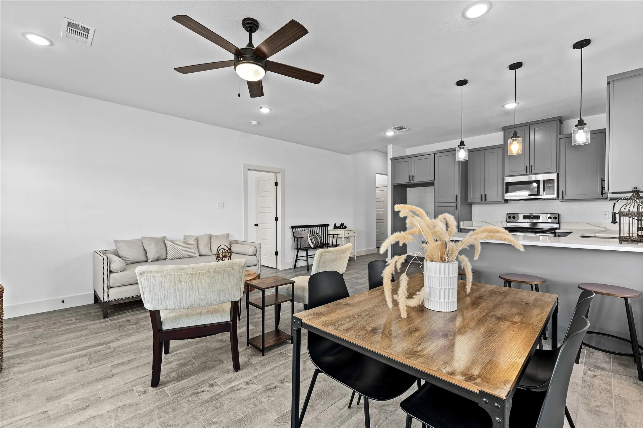 Open-concept living area with wood-finish flooring, recessed lighting, and a ceiling fan