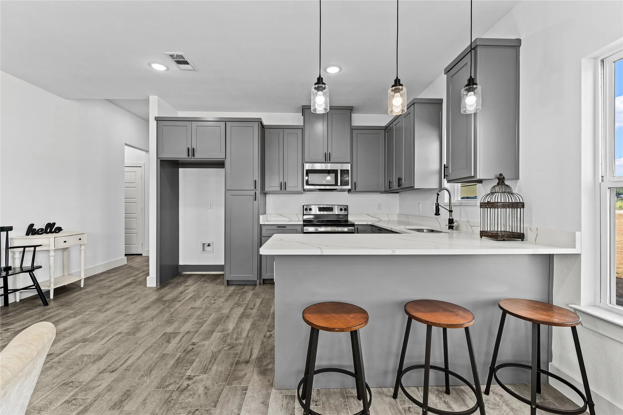 Kitchen featuring grey cabinetry, white countertops, built-in microwave, and pendant lighting