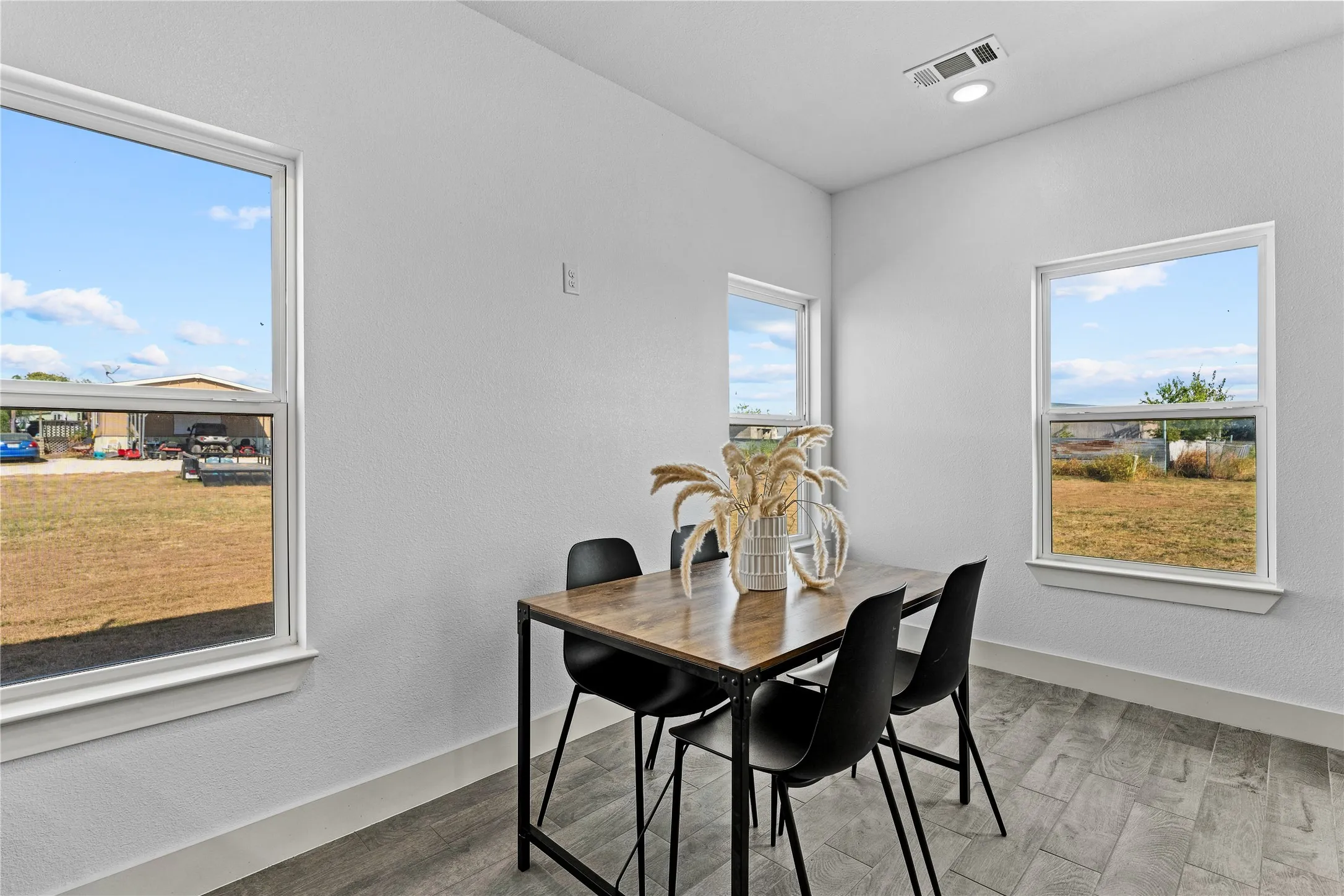 Recessed ceiling light, multiple windows, and wood-finish flooring