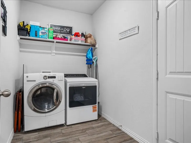 Laundry area featuring wood-finish flooring, a built-in shelf, and a painted paneled door