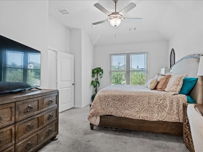 Vaulted ceiling bedroom featuring carpeting, a ceiling fan with integrated lighting, and a window with blinds