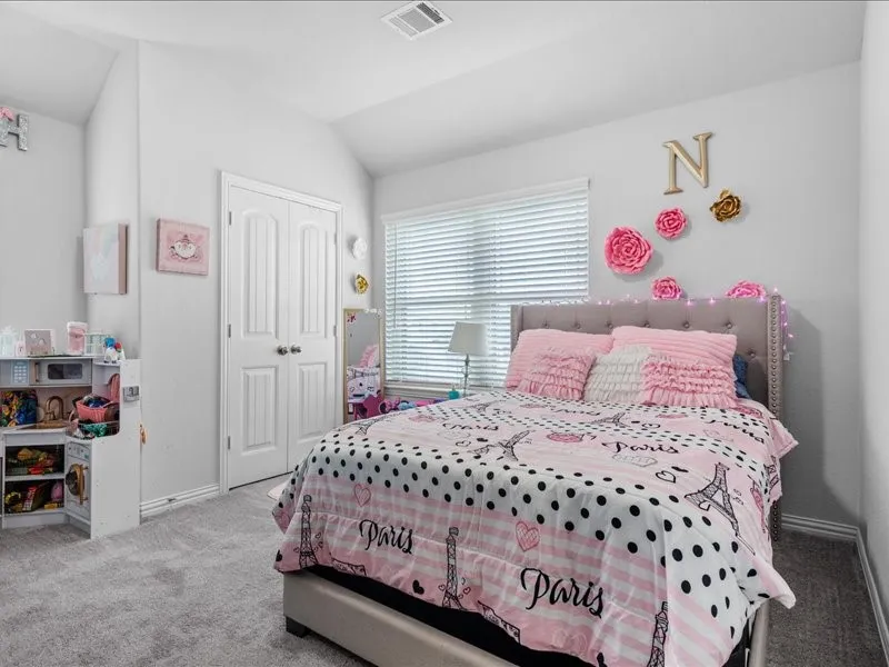 Vaulted ceiling bedroom with light gray carpet flooring, window with blinds, and white paneled bi-fold closet doors