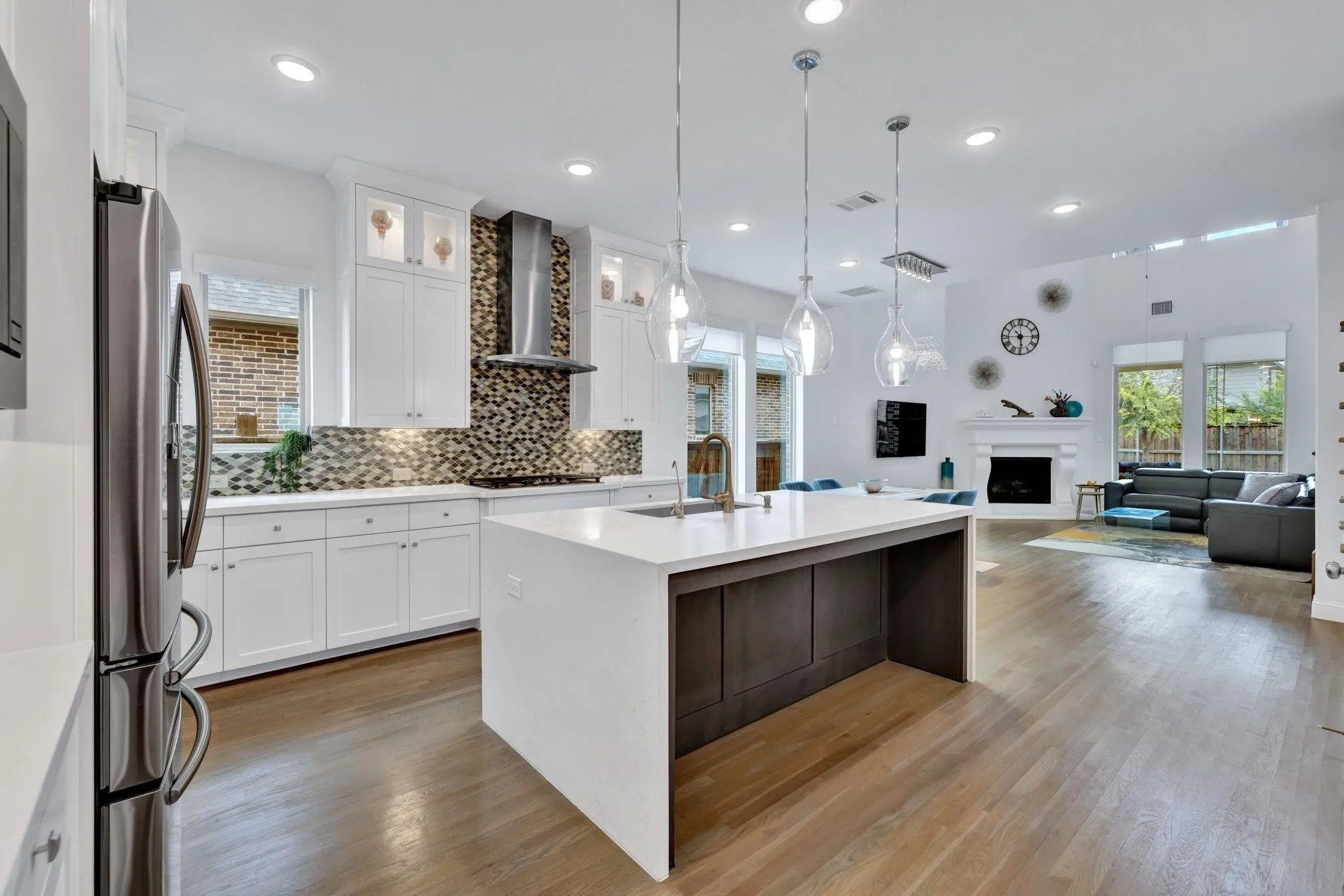 Kitchen with a large central island, white cabinetry, and a patterned backsplash