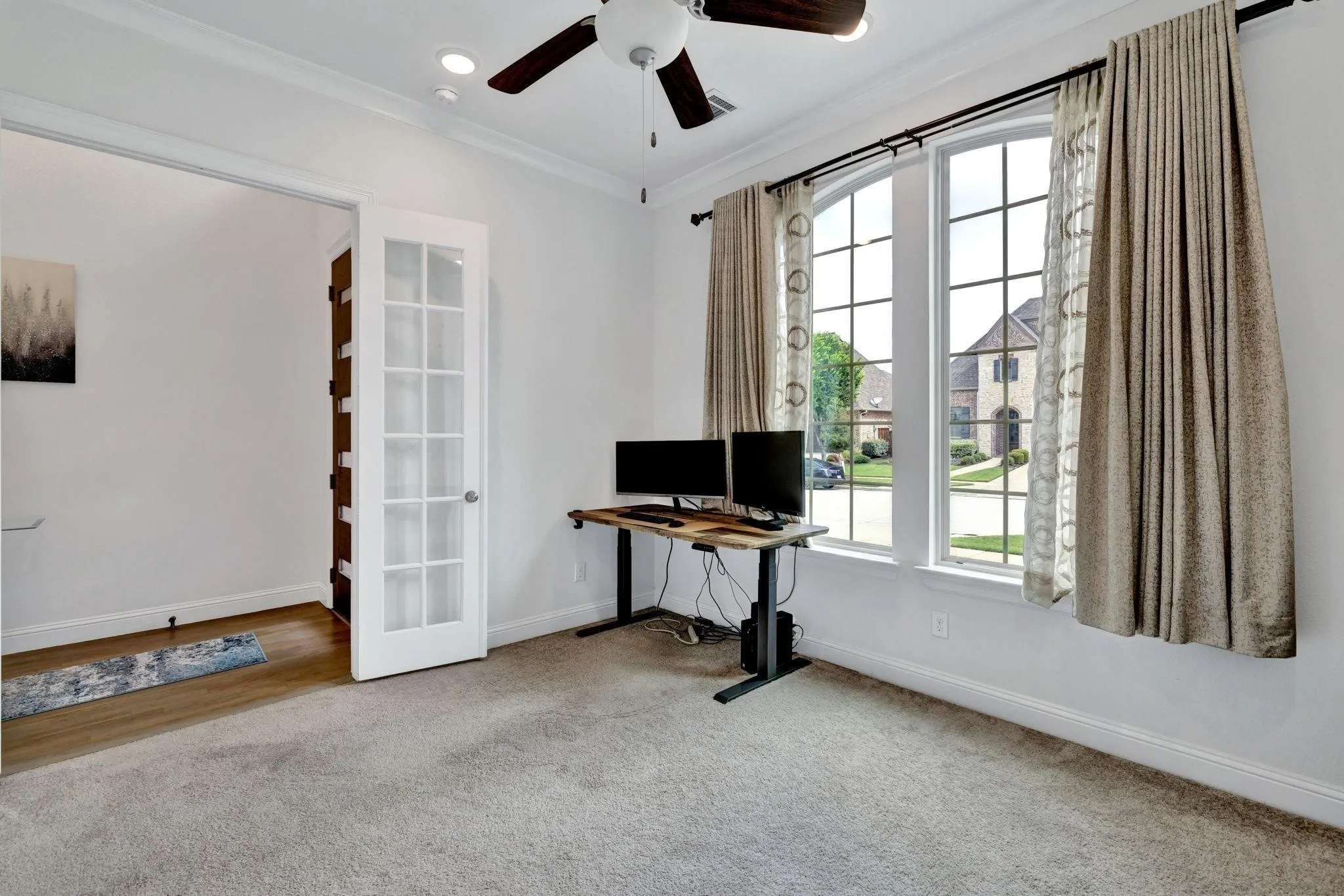 Carpeted room with crown molding, a ceiling fan, and French doors