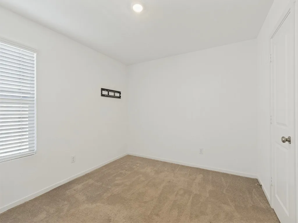 Recessed ceiling lighting, neutral carpet, white walls, and a window with blinds