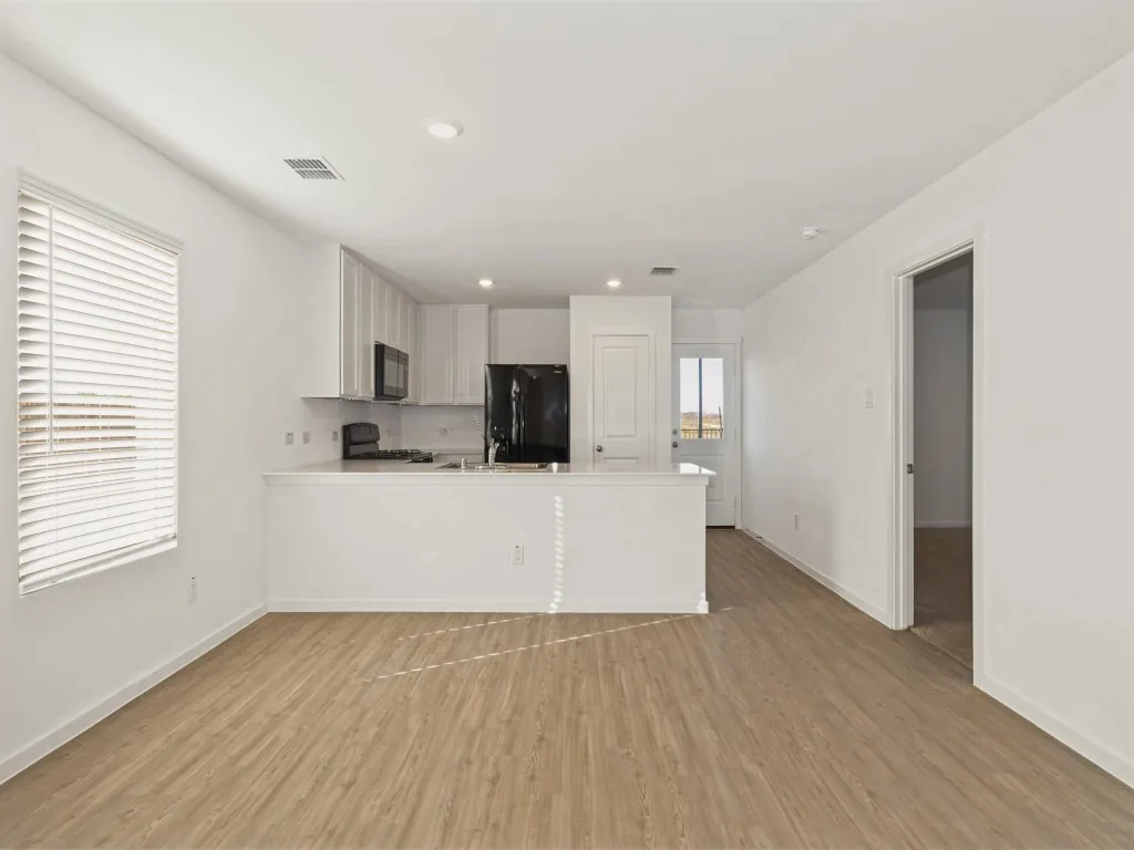 Open-concept living area featuring wood-finish flooring, white walls, and recessed lighting