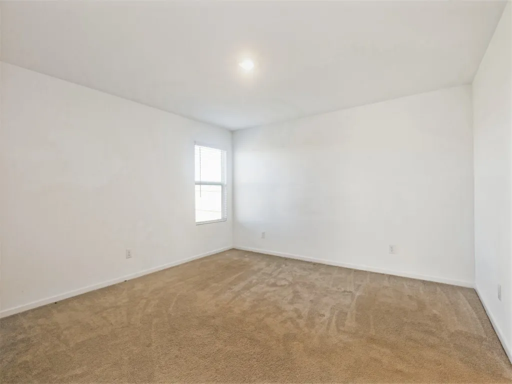 Neutral-toned carpeting, white painted walls, single window with blinds, and recessed lighting