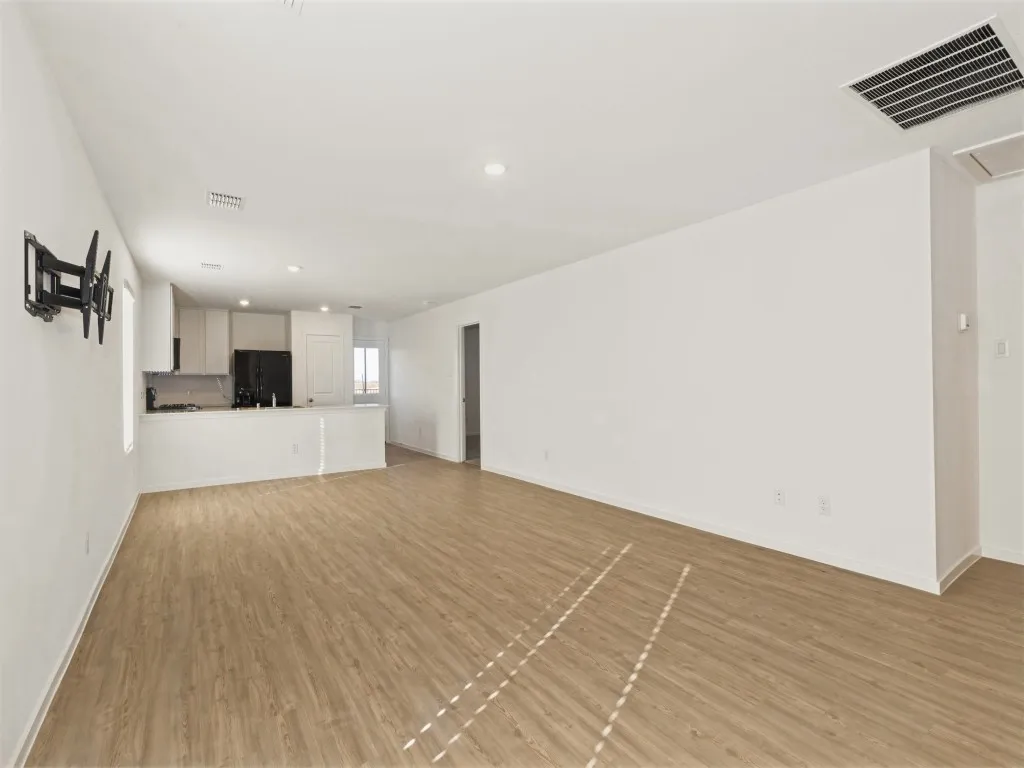 Wood-finish flooring throughout, recessed lighting, white cabinetry, and black appliances