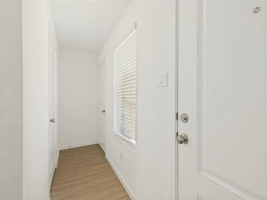 White interior doors, recessed lighting, wood-finish flooring, white window blinds, and brushed nickel hardware
