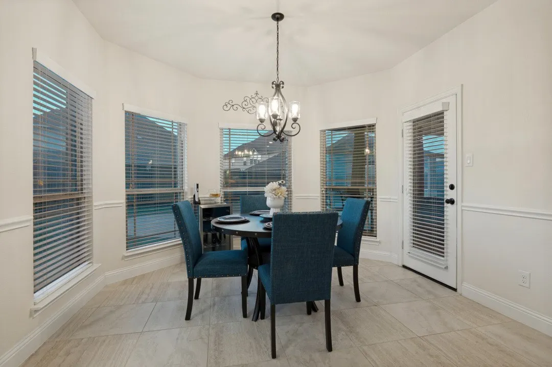 Bay window with multiple windows, glass-paneled door, decorative wainscoting, tile flooring, and overhead chandelier