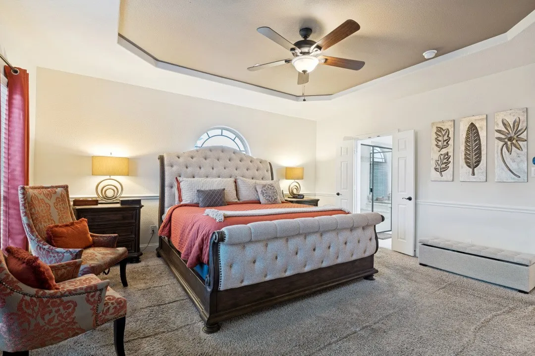 Tray ceiling with ceiling fan and recessed lighting, arched window, and double doors