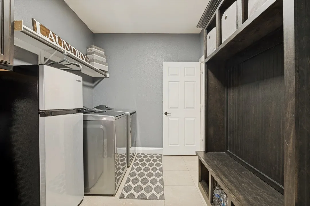 Laundry area featuring built-in shelving, a built-in bench, and light-toned tile flooring