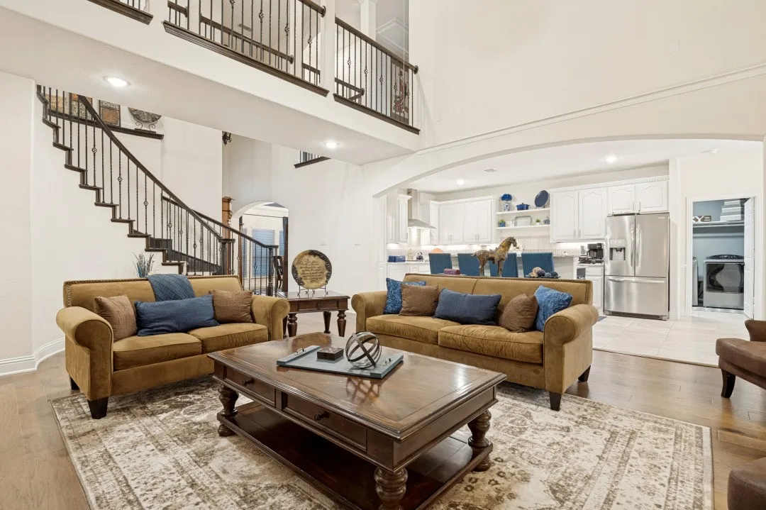 Two-story living area featuring wood-finish flooring, a grand staircase with wrought iron balusters, and a recessed lighting system