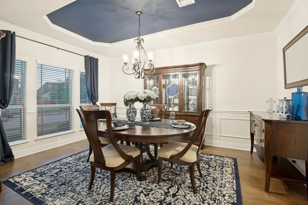 Tray ceiling with accent color, crown molding, wood-finish flooring, wainscoting, and large windows