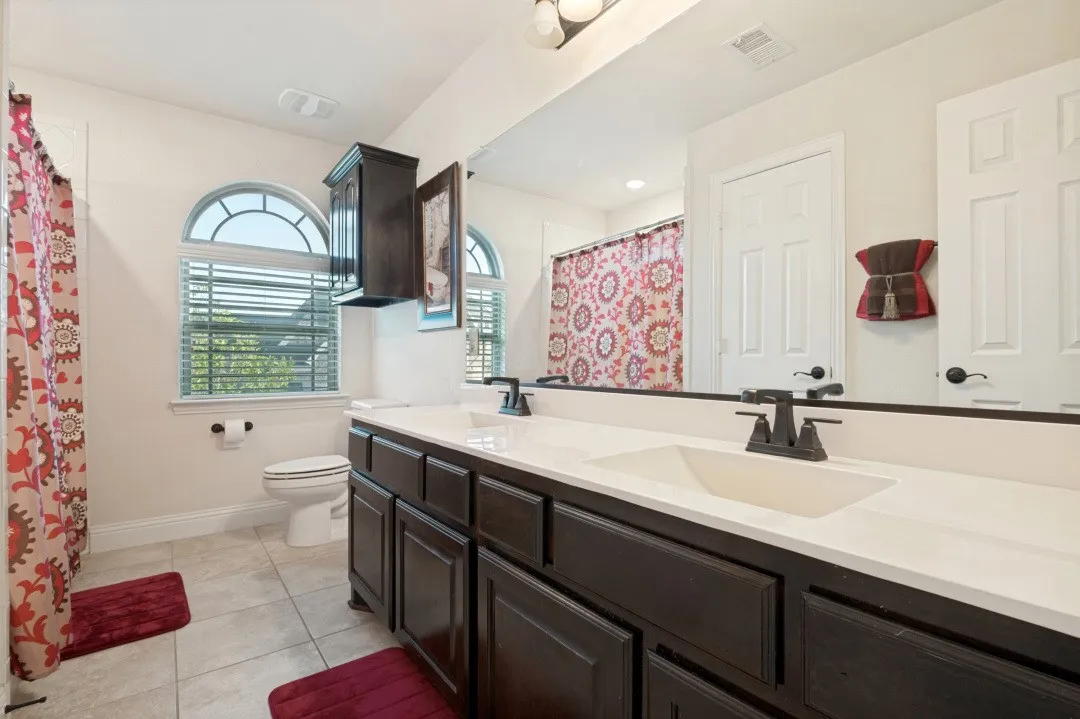 Double vanity with integrated sinks, dark wood-finish cabinetry, and matte black hardware