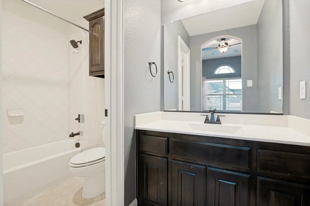 Bathroom vanity with an integrated sink, dark wood-finish cabinetry, and a full-width mirror