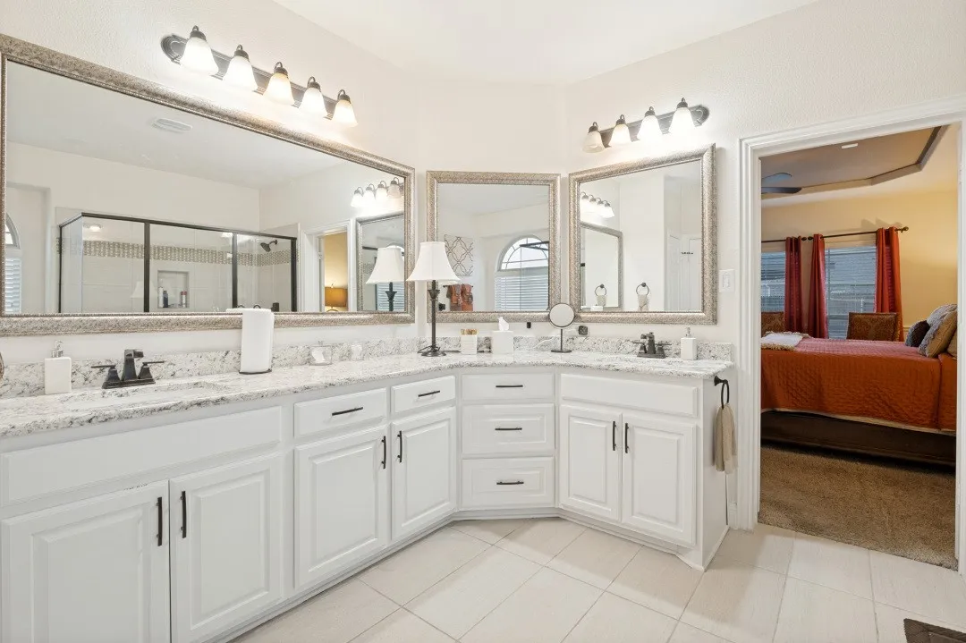 Dual white vanities with black fixtures, granite-look countertops, and framed mirrors