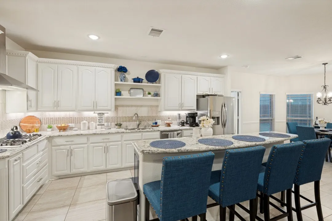 White cabinetry, stainless steel appliances, central island with seating, tile flooring, and recessed lighting