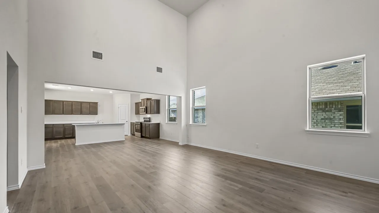 Vaulted ceilings, wood-finish flooring, two windows, recessed lighting, and a kitchen featuring dark wood cabinetry and white countertops